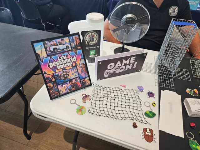 Close-up of the LTK table: the LTK PestWorld House poster, Game On sign and bug stickers and keychains