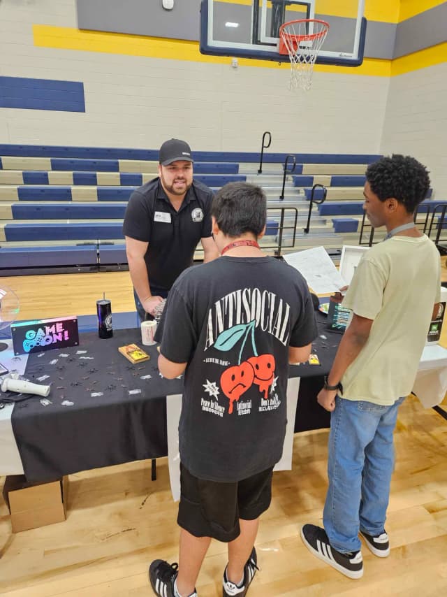 Marcus at the LTK table at a middle school career day, with live traps, mouse traps and a crocheted rat dissection