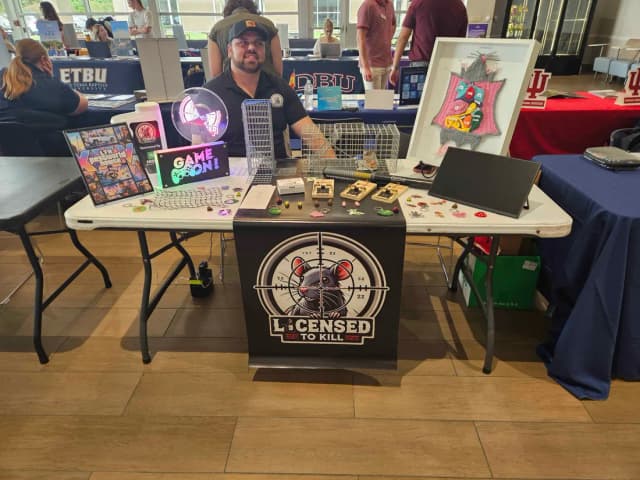 The LTK table at a college and career fair: Licensed to Kill banner, Game On sign, traps and the LTK PestWorld House poster