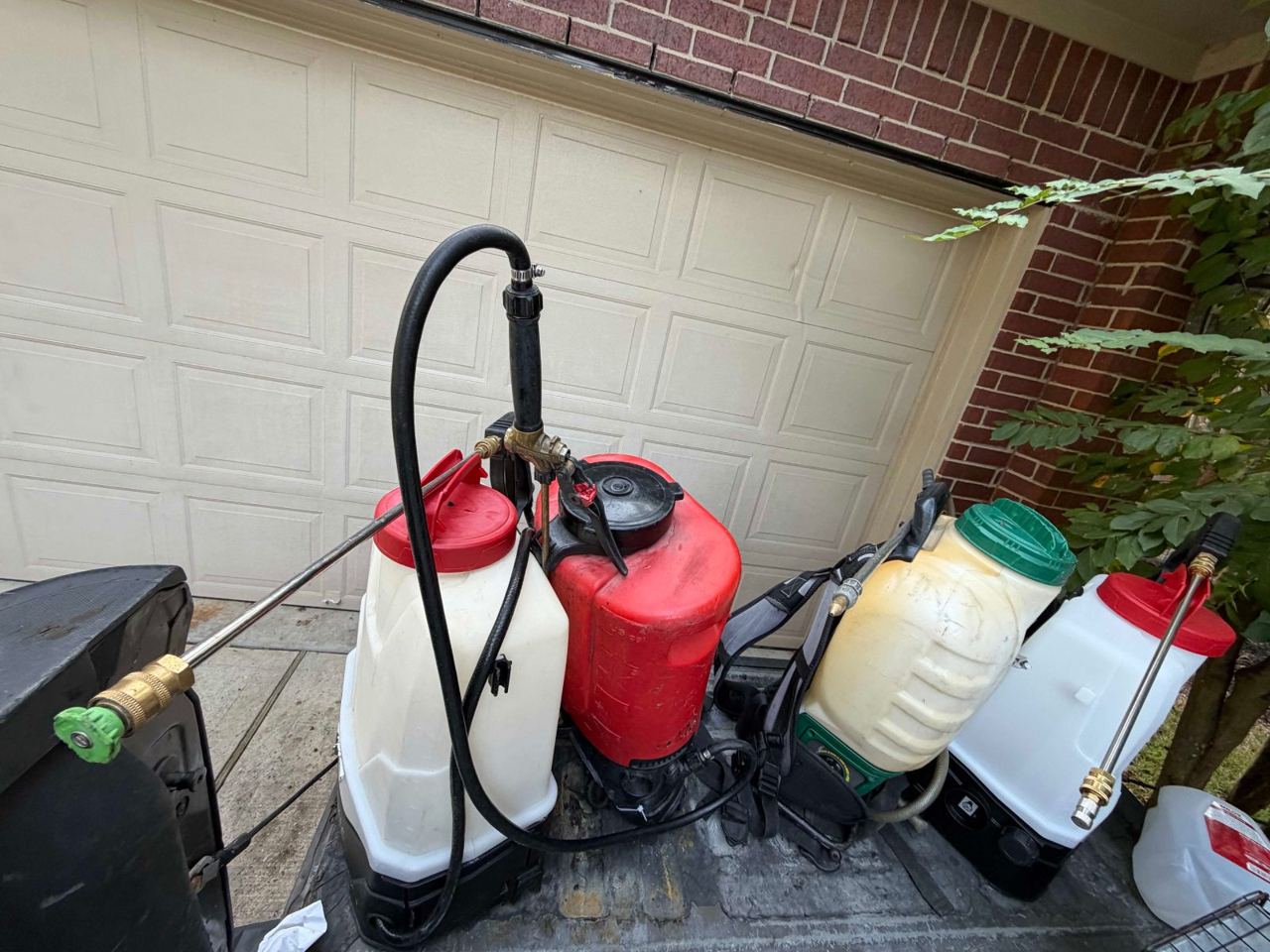 Four backpack sprayers lined up in a pickup bed, ready for the day